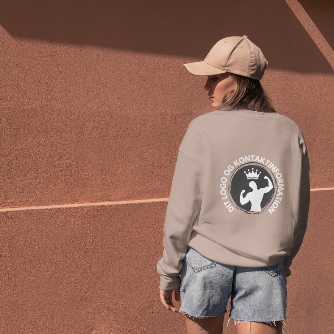 Billede af en kvinde med en sweater og kasket, der har et logo på ryggen, hvor der står "DIT LOGO OG DINE KONTAKTINFORMATIONER"